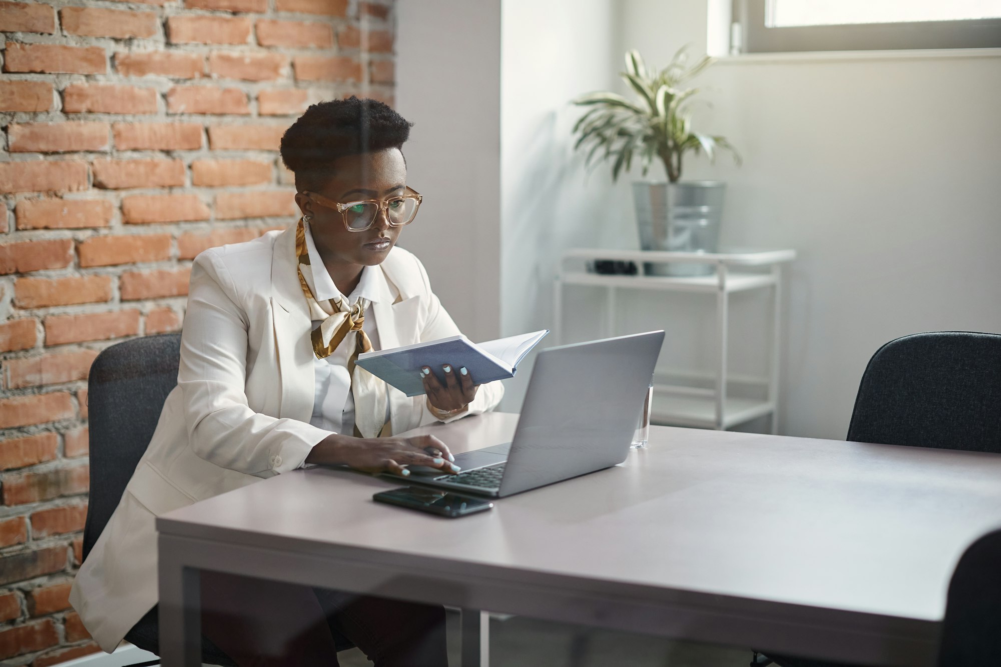 Black businesswoman working on laptop at corporate office.